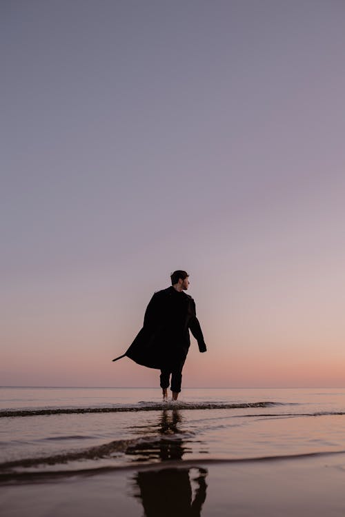 Man Walking on Sea Shore at Dusk