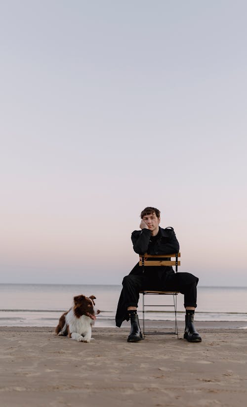 Man on Chair on Beach with Dog