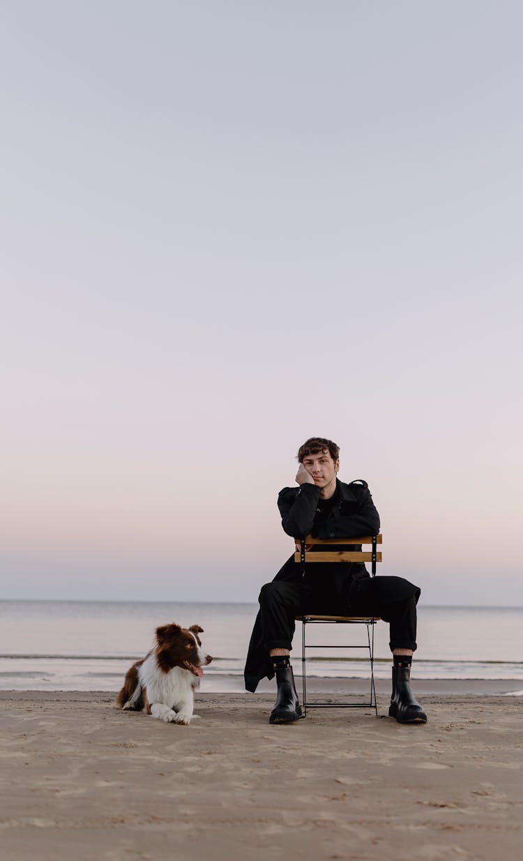 Man On Chair On Beach With Dog