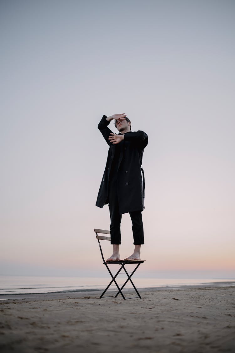 Man Standing On Chair On Beach