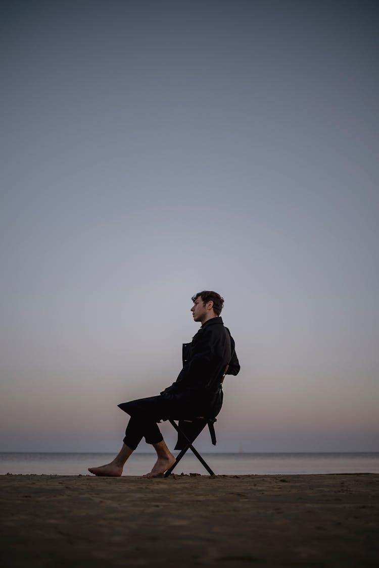 Man Sitting On A Chair On A Beach 