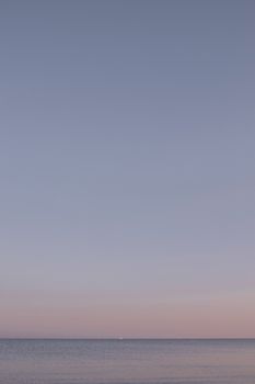 Serene view of the ocean at sunset under a vast clear blue sky, perfect for peaceful themes.