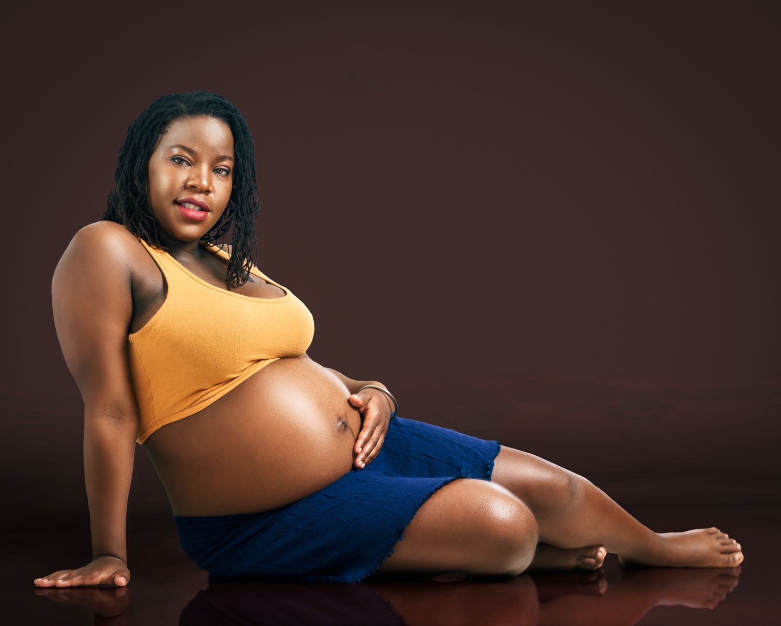 Pregnant woman seated with legs visible, matching compression sock choices for travel while pregnant. Photo: Pexels.