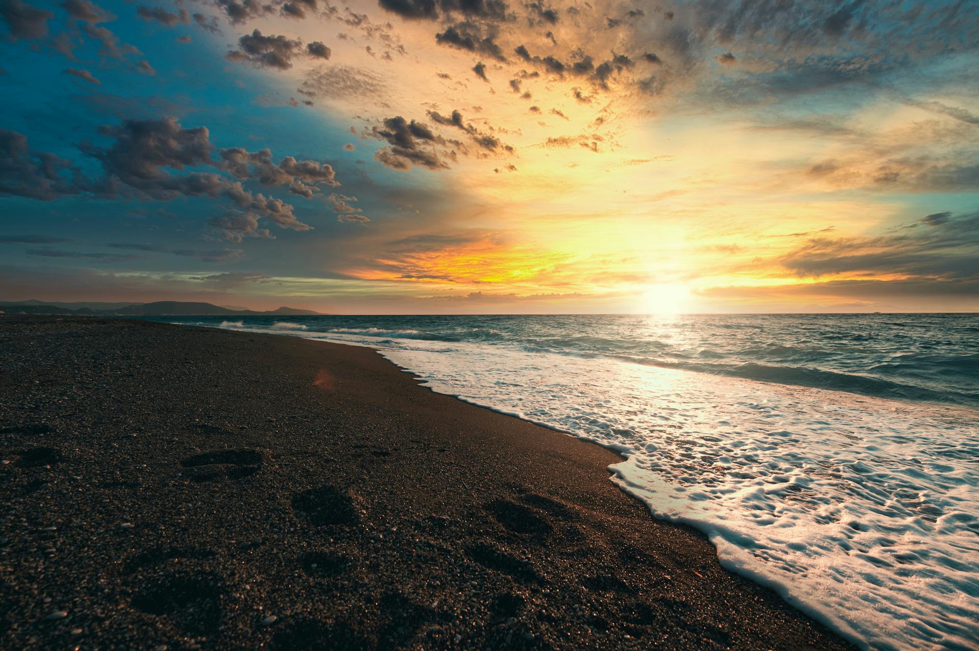 Beautiful sunset over a sandy beach in Rhodes, Greece with vibrant skies.