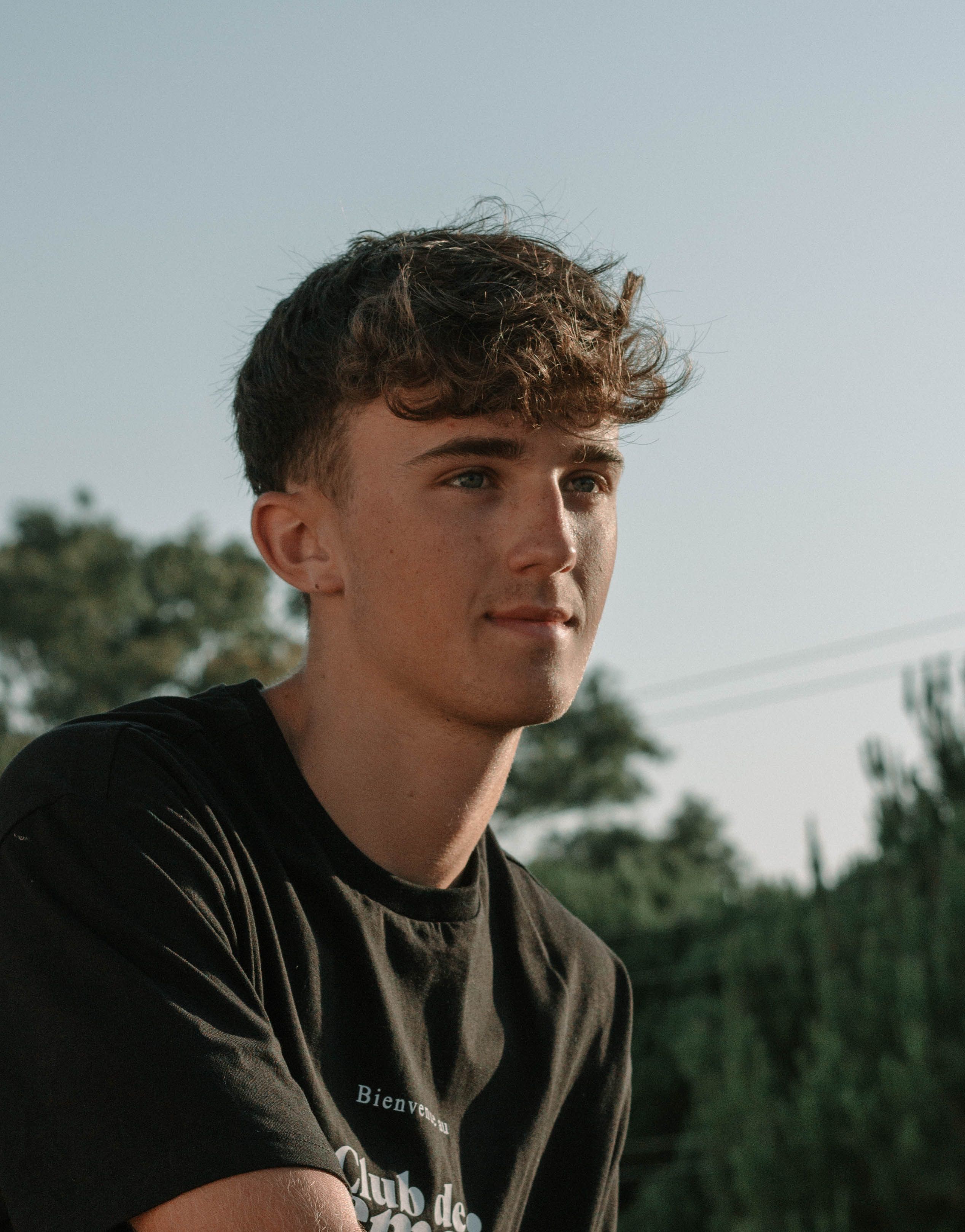 Portrait of a young man in a black shirt with a natural outdoor background in Mijas, Spain.