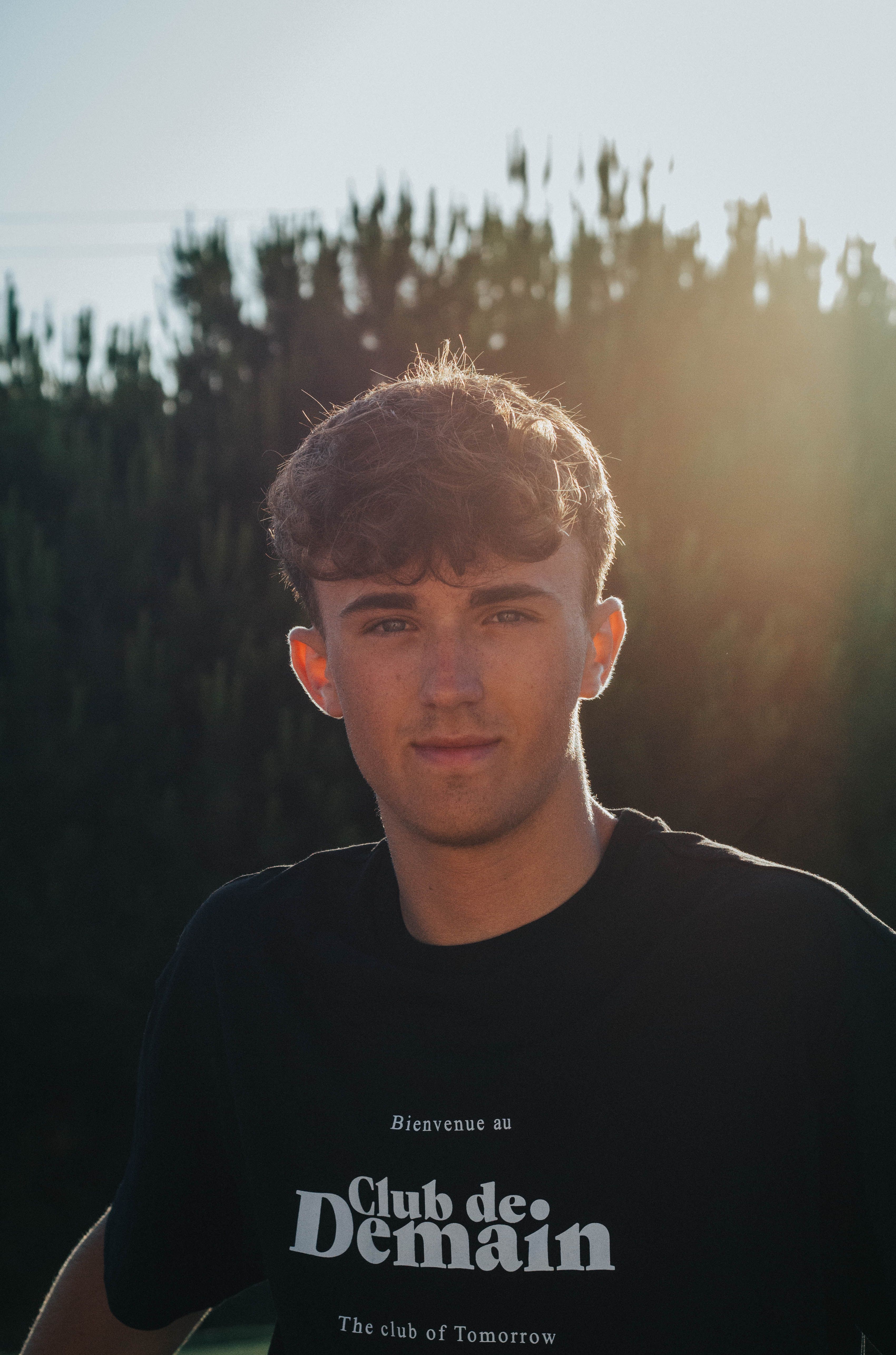 Portrait of a young man in Mijas, Spain at sunset with trees in the background.