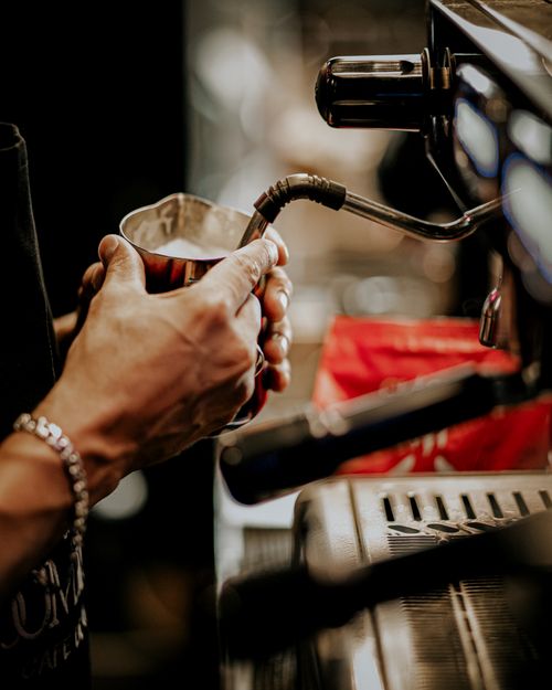 Free Barista steaming milk in Baku coffee shop setting, close-up hands shot. Stock Photo