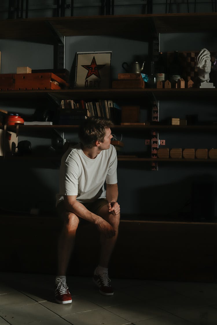 Man Sitting And Looking At His Collection On Shelves