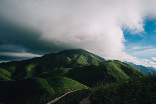 Free Discover the breathtaking view of lush green mountains under dramatic clouds. Stock Photo