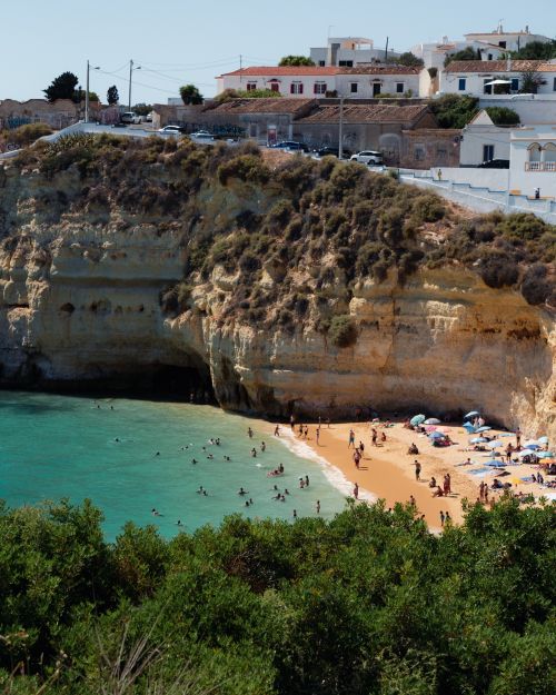 Free Beautiful aerial view of a scenic beach with turquoise waters, cliffs, and people enjoying summer. Stock Photo