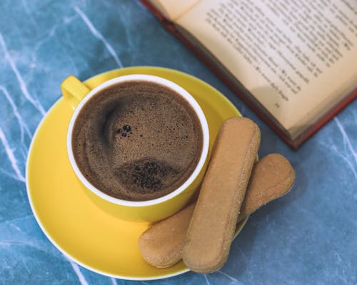 Free Cup of Coffee and Biscuits Near a Book Stock Photo