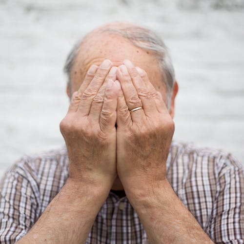 Elderly Man Covering His Face with His Hands