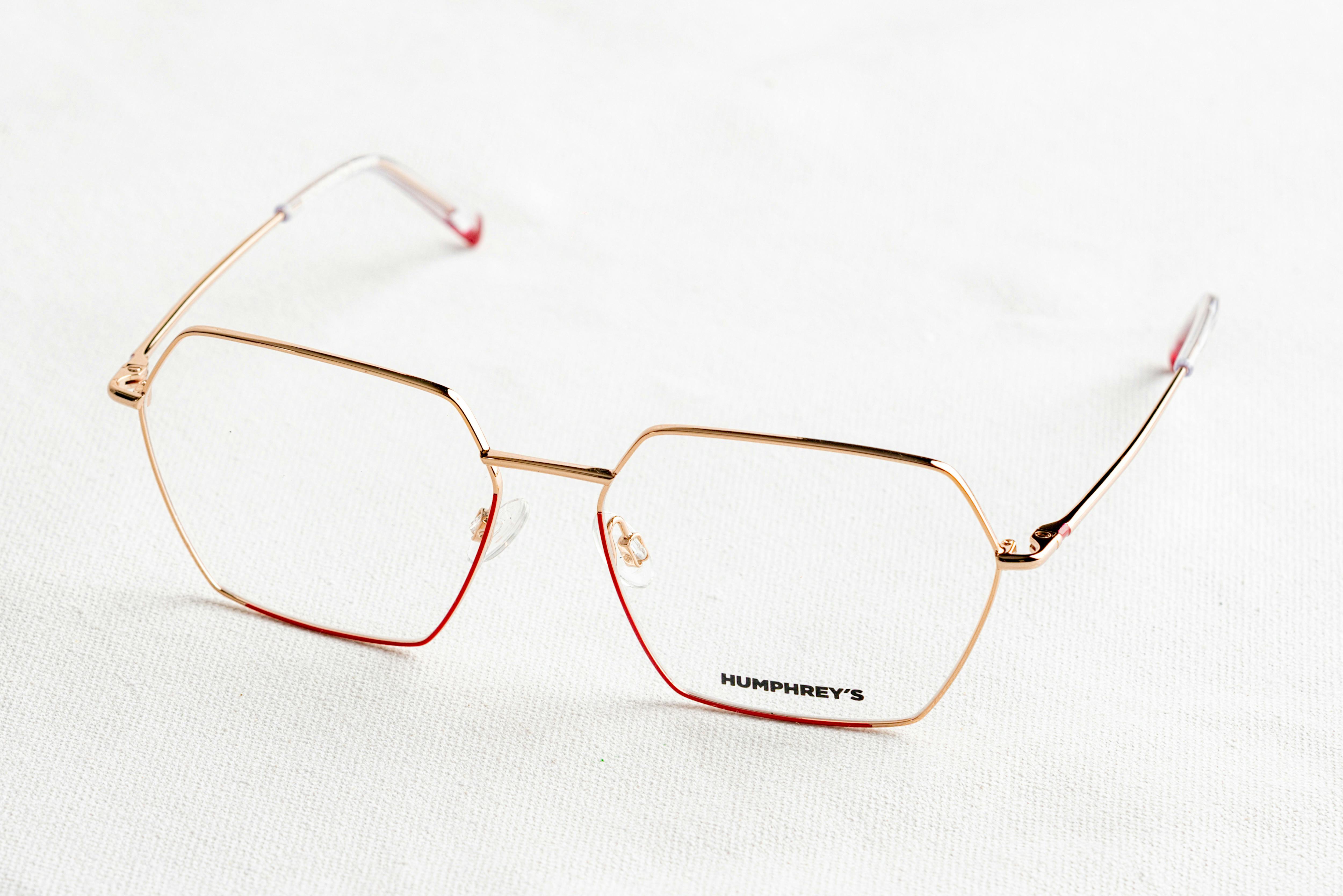 Minimalist close-up of gold-framed eyeglasses on a white surface with a sleek design.
