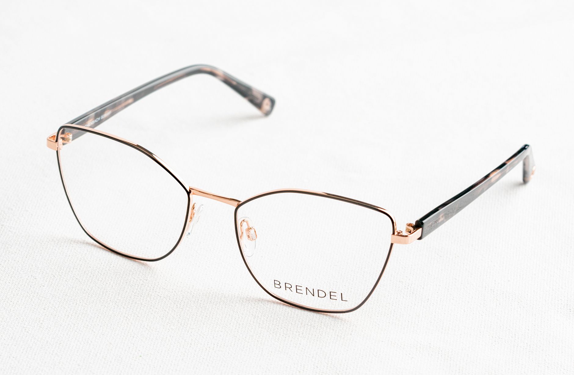 Close-up of stylish gold eyeglasses with 'BRENDEL' branding on a clean white surface.