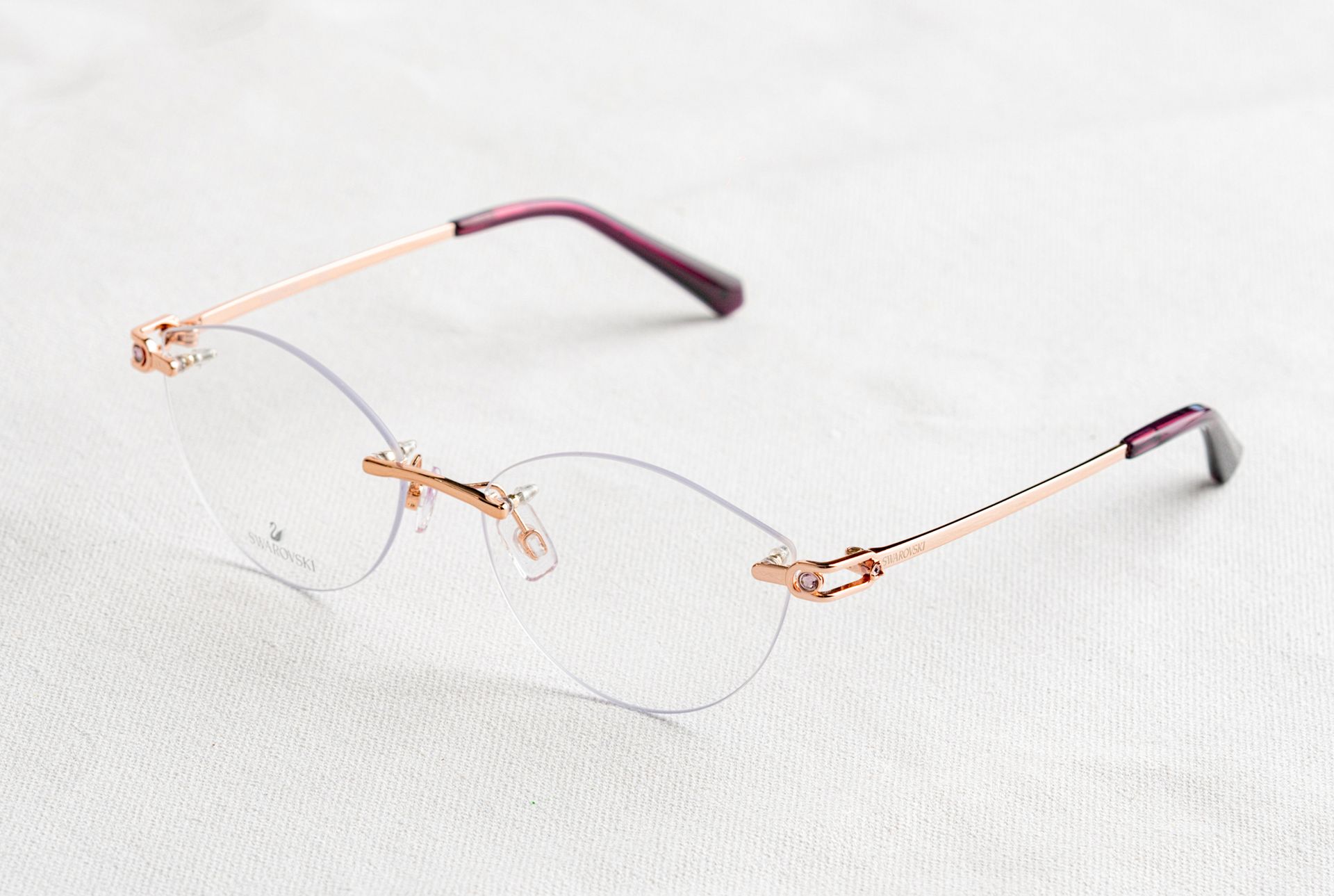 Close-up of stylish rimless eyeglasses with golden temples on a white background.