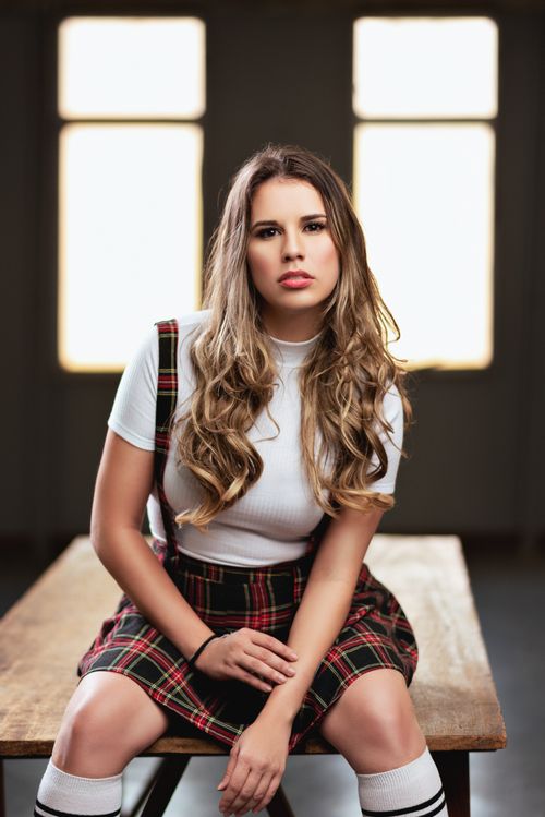 Free Fashionable young woman with long hair posing indoors on a wooden table. Stock Photo