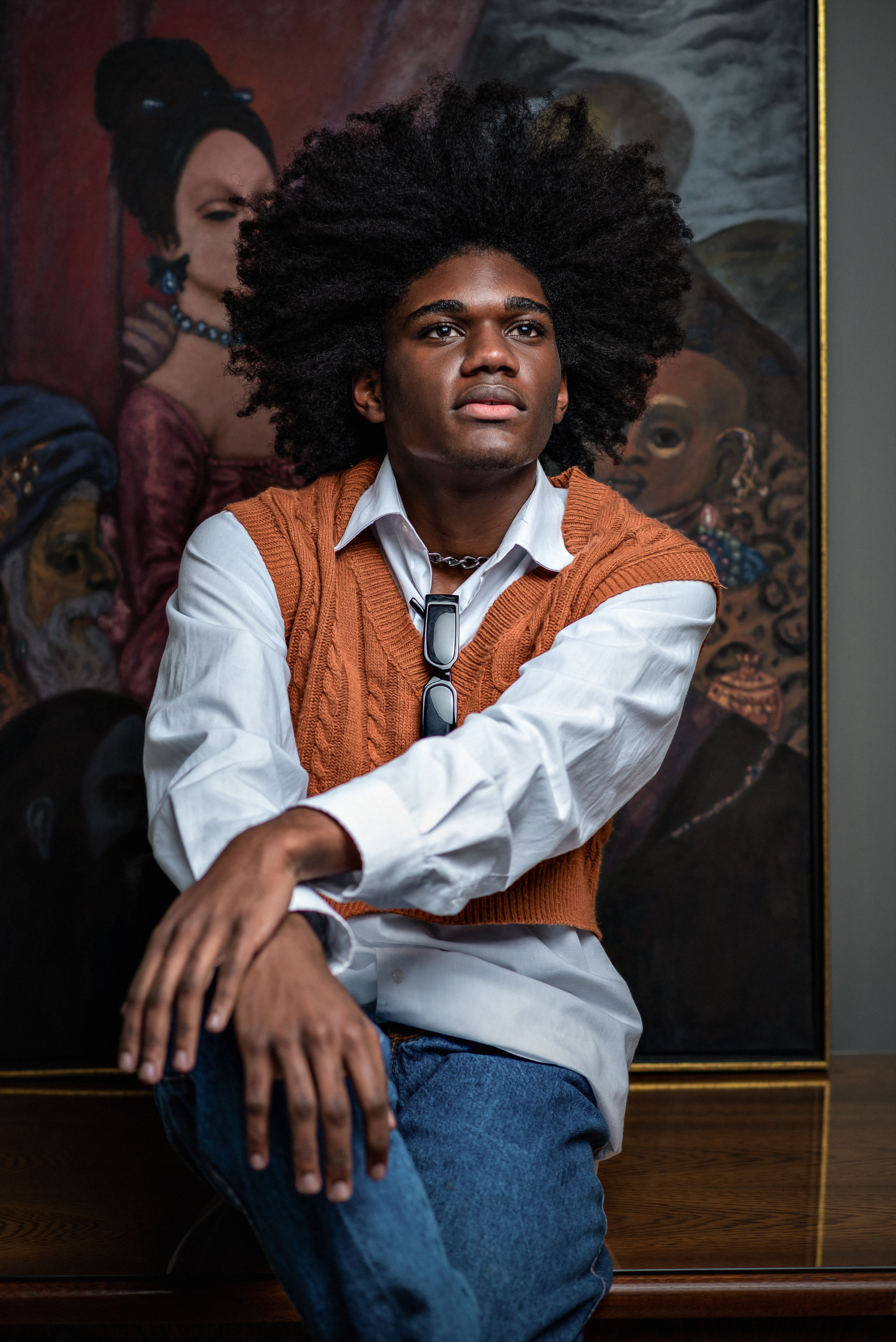 Elegant portrait of a young man in an art gallery, showcasing fashion and style.
