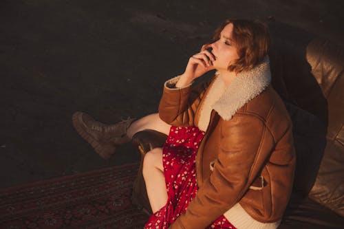 Бесплатное стоковое фото с диван, женщина, коричневая кожаная куртка