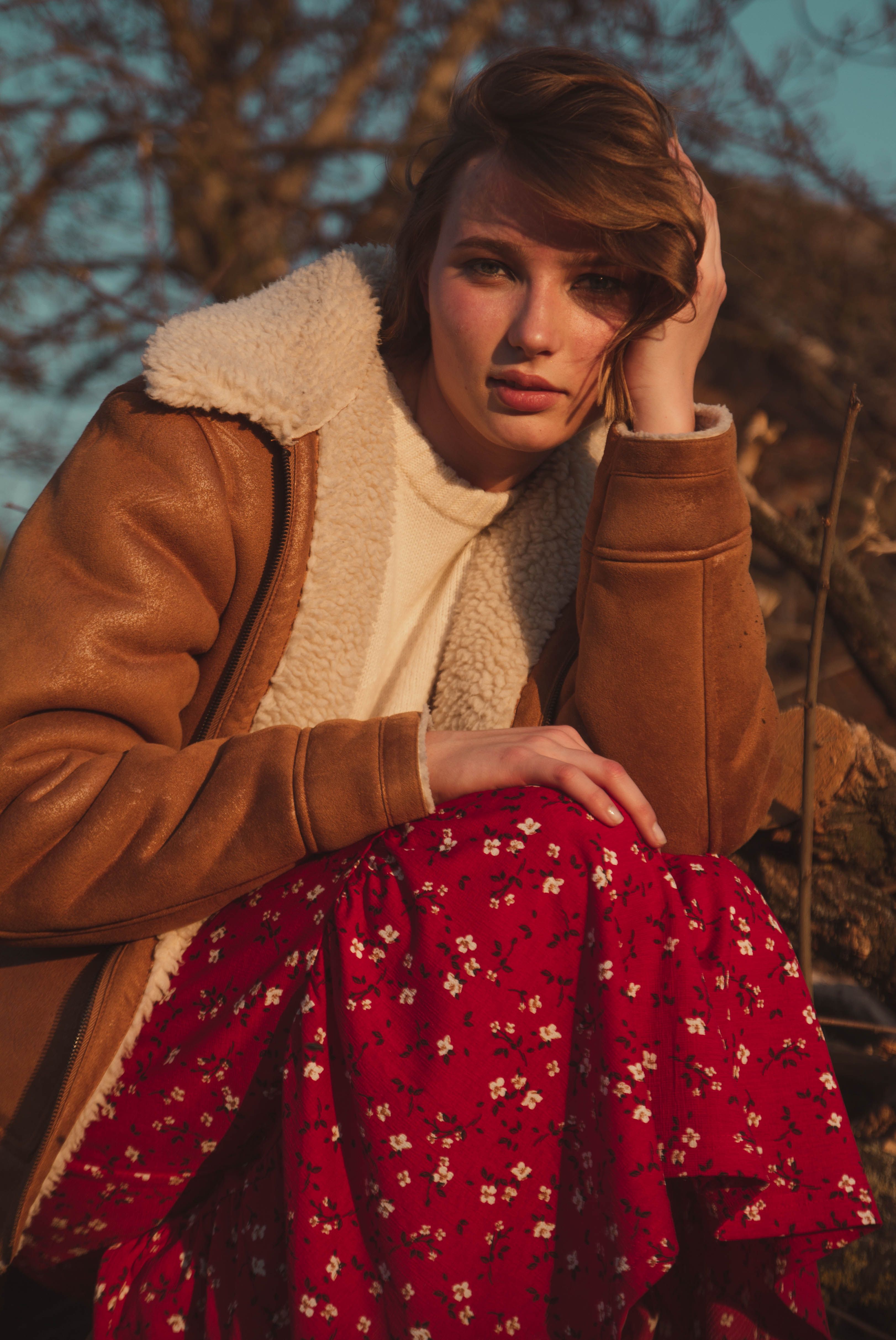 Elegant portrait of a woman in autumn attire enjoying the outdoors with warm lighting.