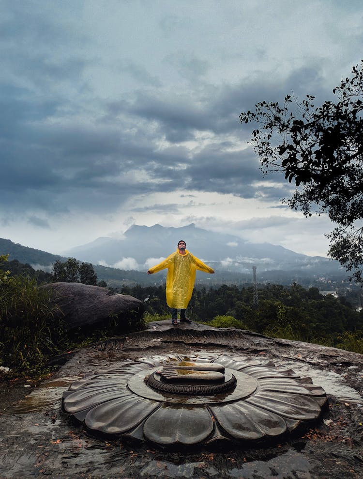 Person In Yellow Coat Standing On Top Of Hill