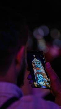 Man photographing Galata Tower in Istanbul using smartphone. Night cityscape focus.