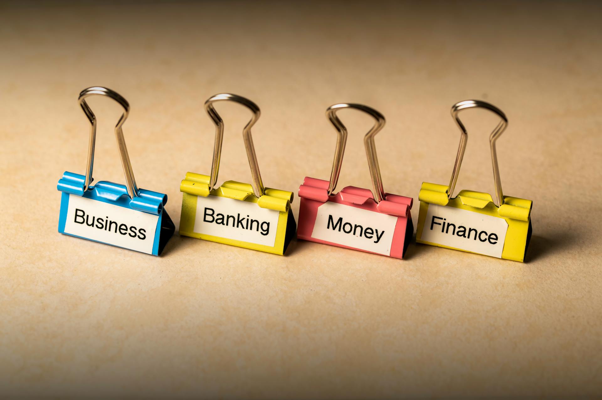 Close-up of binder clips with labels for business, banking, money, and finance concepts.