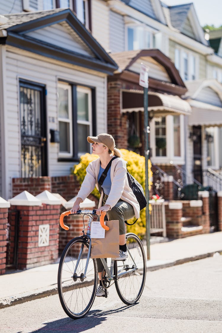 Woman Cyclist With Paper Bag Riding Road In Town