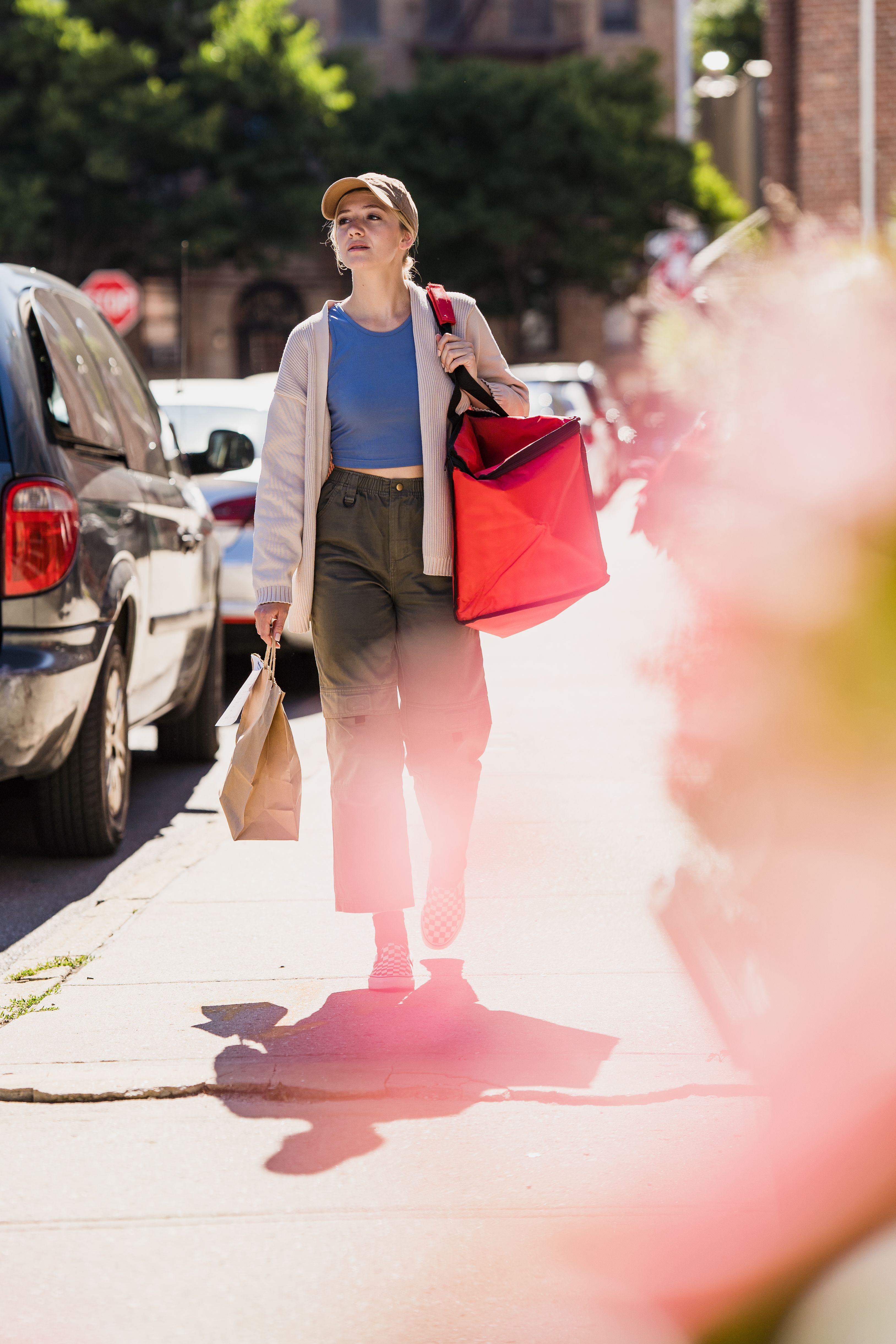 Young woman walking outdoors with shopping bags on a sunny day, showcasing urban lifestyle.