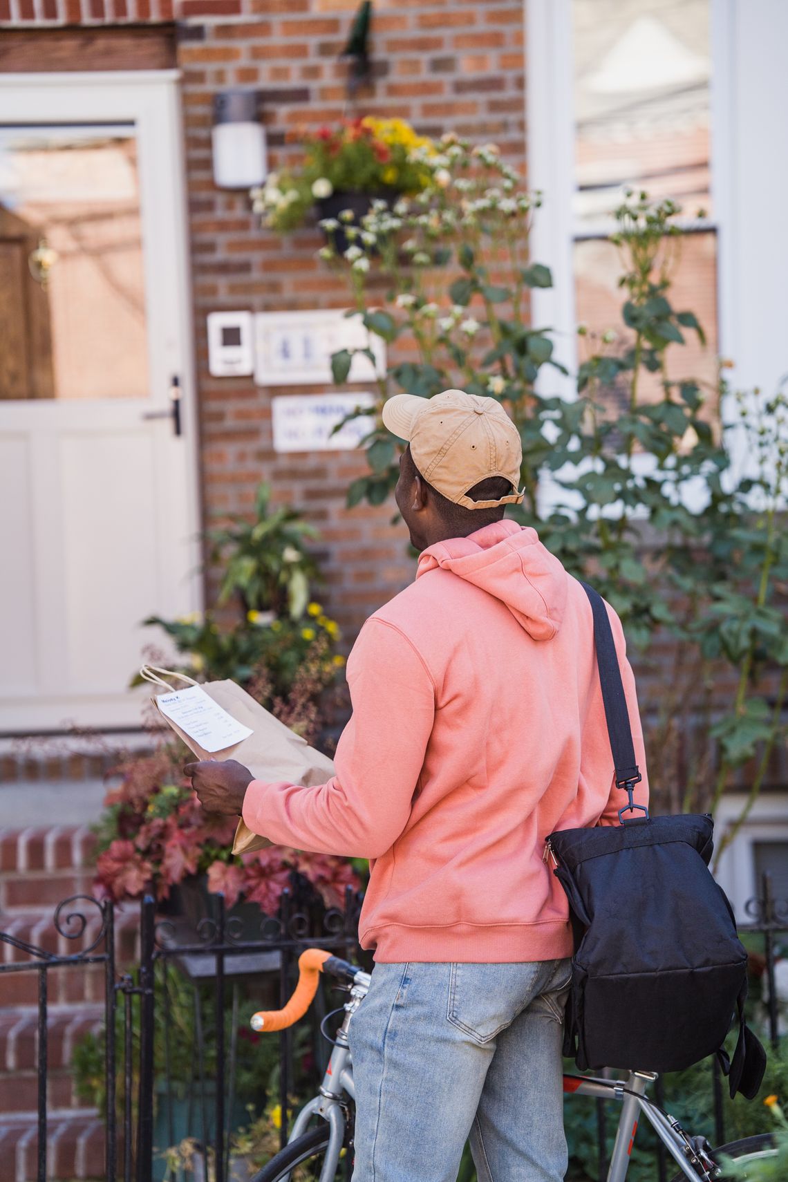 Bicycle courier standing at a residential doorway with a package ready for delivery
