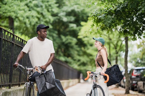Food Delivery Man and Woman on Bicycles Carrying Food Delivery Bags Talking 