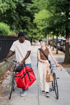 Two individuals with bikes strolling down a city sidewalk for food delivery.