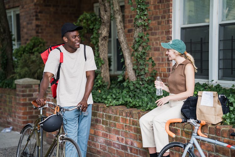 Smiling People With Bikes Talking Outdoors