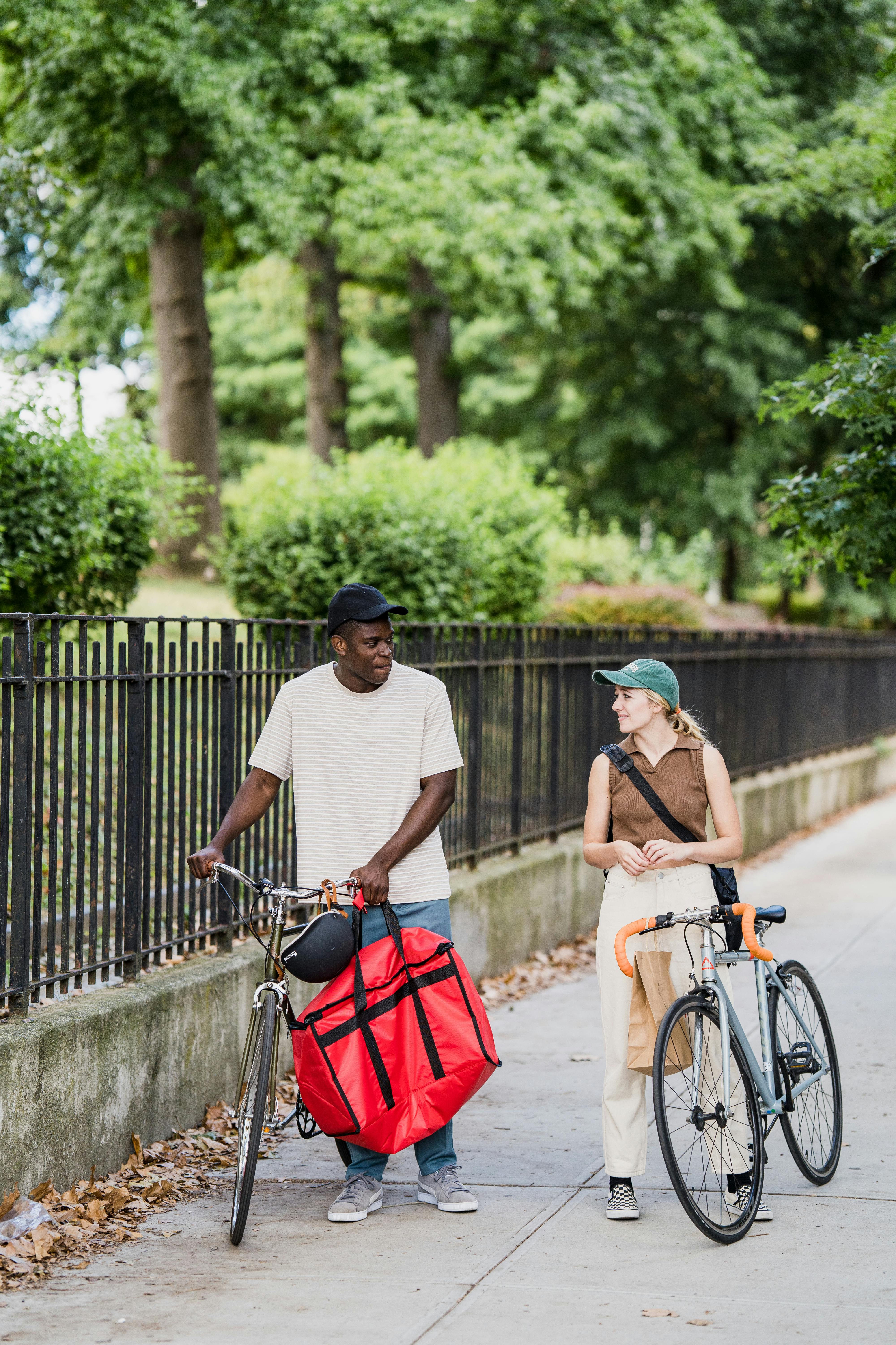 Food Delivery Man and Woman on Bicycles Carrying Food Delivery Bags