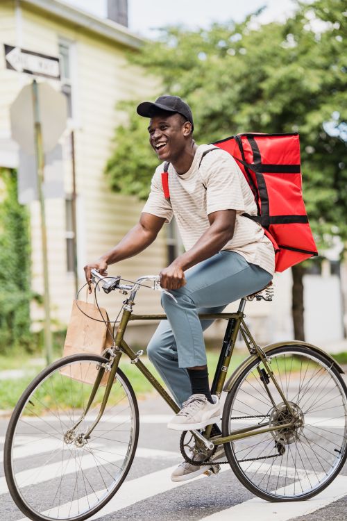 Courier Riding Smiling Courier with Backpack Riding Bike · Free Stock Photo