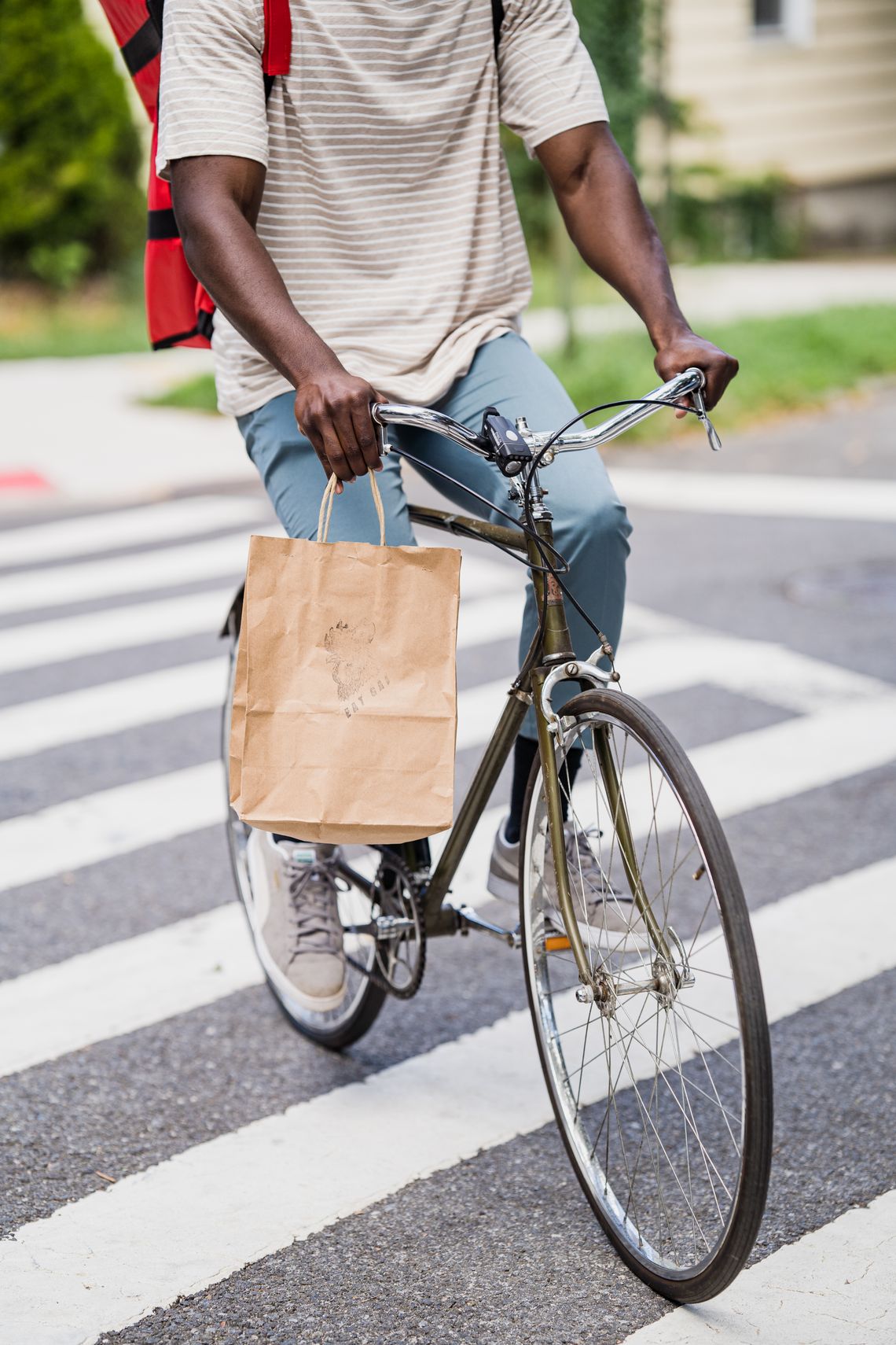 Bicycle courier carrying a package through an urban crosswalk