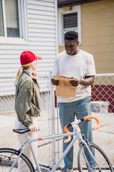 A female bicycle courier delivers a package to a male customer outdoors.