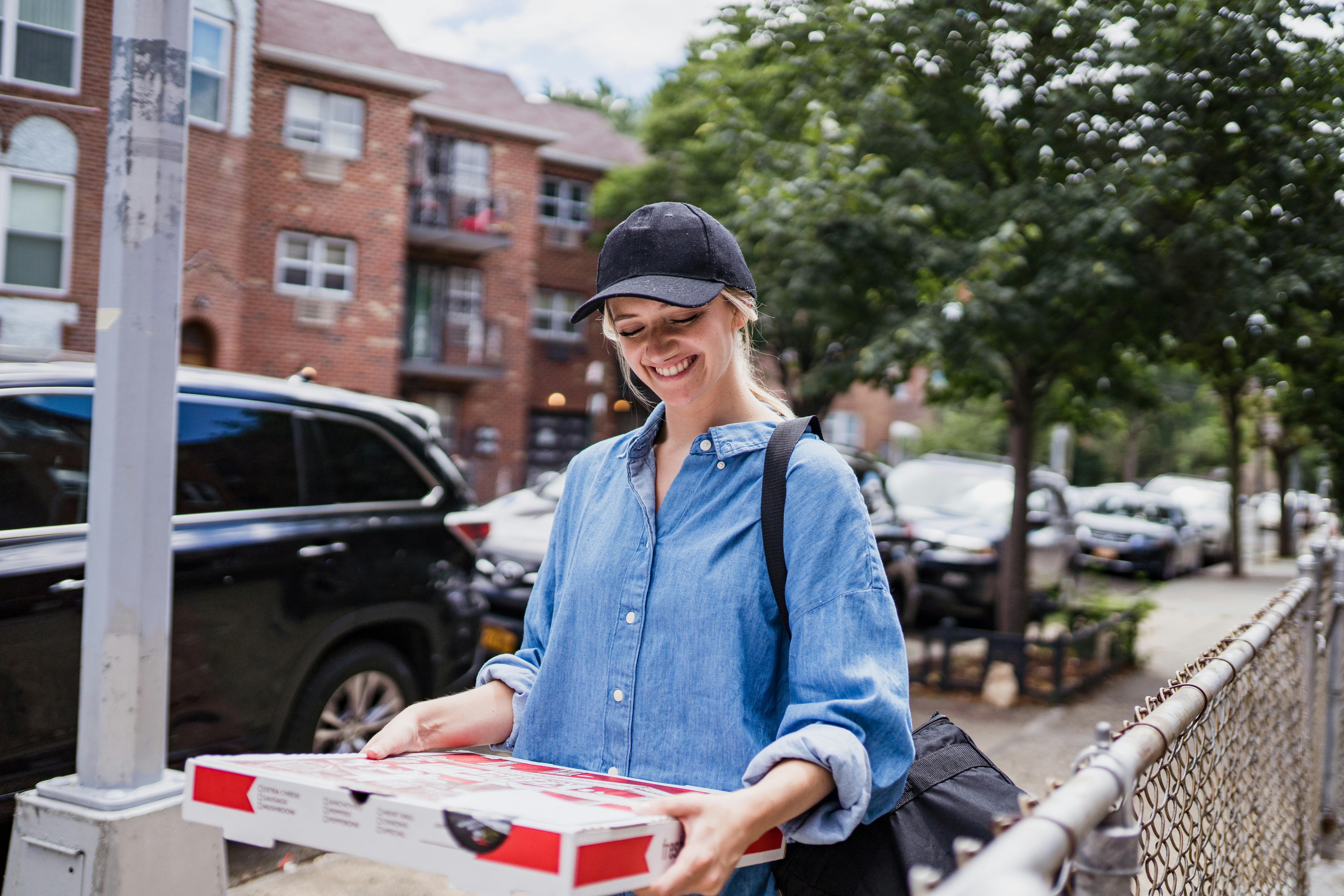 smiling woman carrying pizza