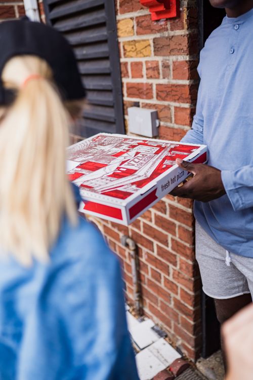 Free A delivery person hands a fresh pizza to a customer at the door, showcasing home delivery service. Stock Photo