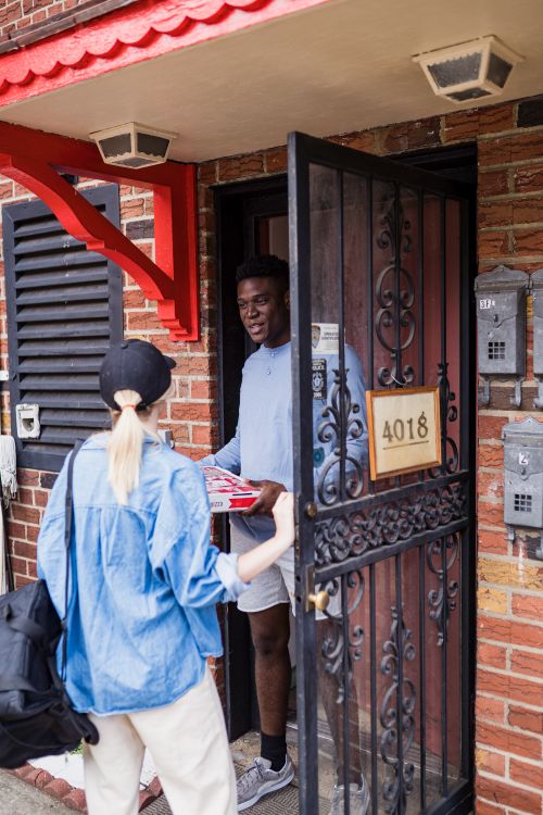 Free A man receives a package from a delivery woman at his home entrance. Stock Photo