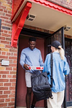 A friendly doorstep delivery interaction with a woman handing a parcel to a man.