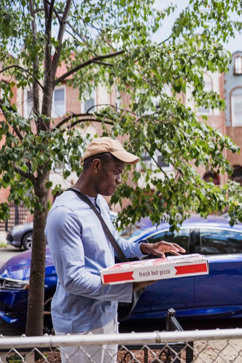 Free A person delivering pizza in a city neighborhood captures the essence of urban life. Stock Photo
