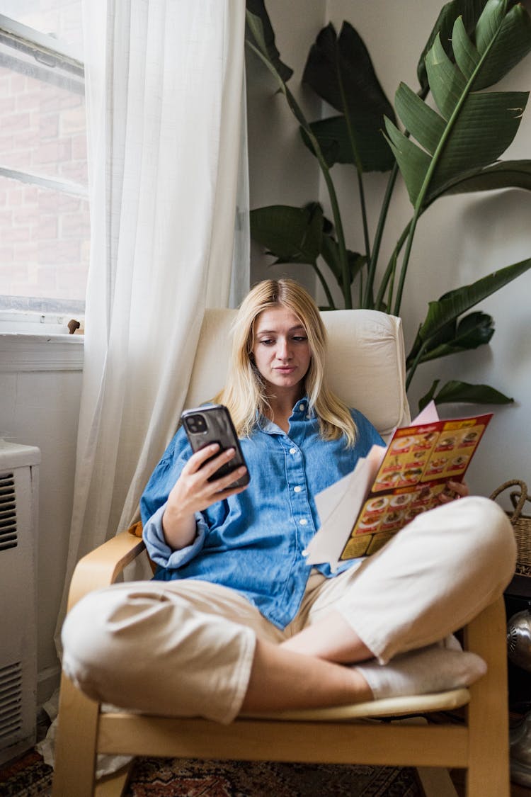 Woman Sitting In Armchair And Ordering Food On Smartphone