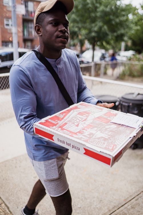 Free Young man delivering pizza outdoors in an urban setting, showcasing modern lifestyle and convenience. Stock Photo