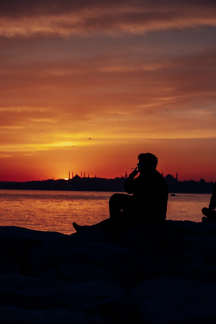 Silhouette Of Person Smoking Cigarette At Sunset