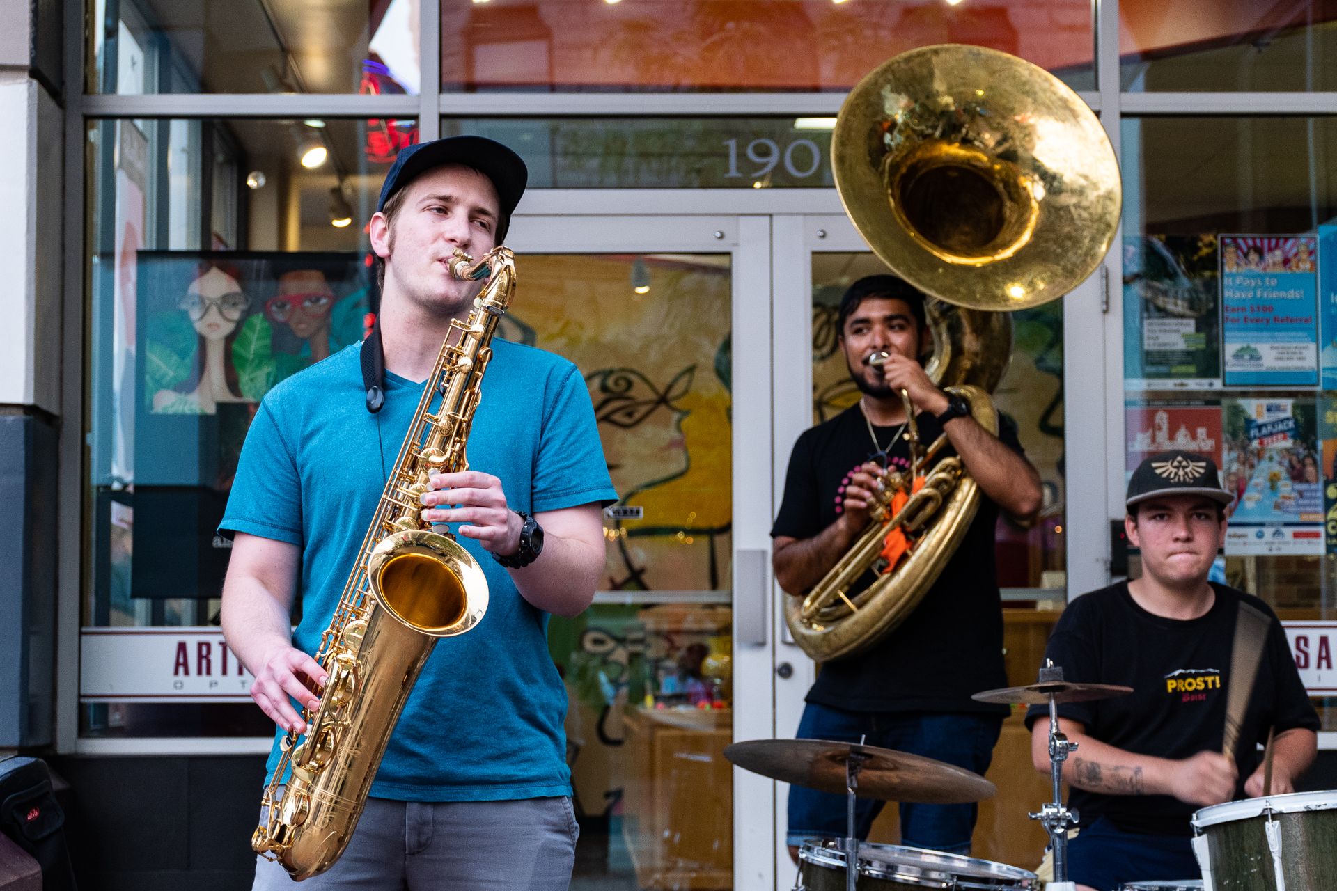 A lively street jazz band with saxophone, tuba, and drums performing outdoors.