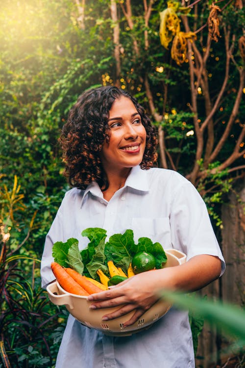 Woman in White Button Up Shirt Holding A Container Full of Vegetables