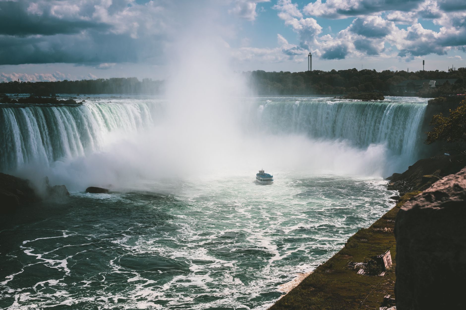 A breathtaking view of Niagara Falls showcasing the powerful waterfall with a tourist boat in the mist.