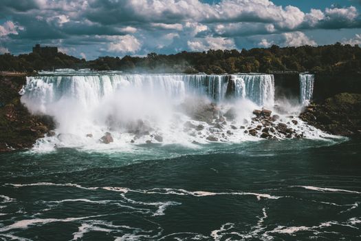 Captivating shot of the iconic Niagara Falls cascading powerfully against a backdrop of lush greenery.