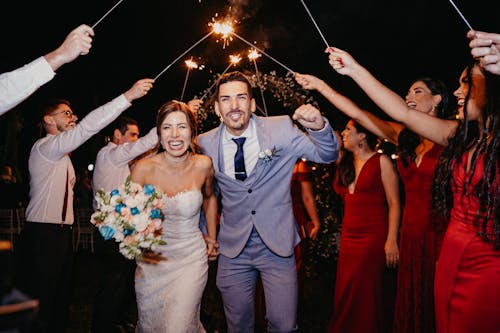 Free Man in Blue Suit Jacket Standing Beside Woman in White Tube Dress Holding Lighted Sparkler Stock Photo