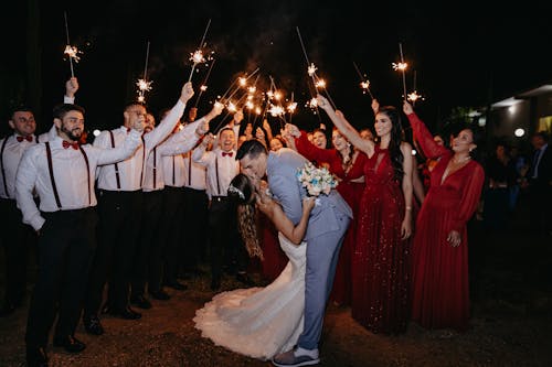 Newlyweds Kissing and People with Sparklers behind